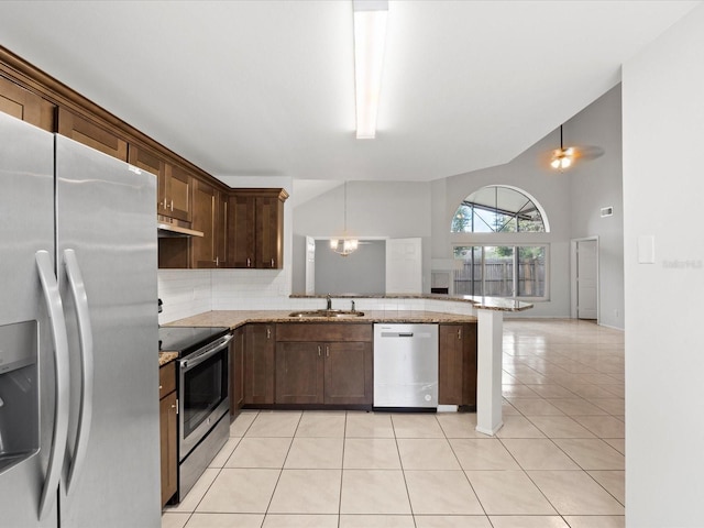 kitchen with hanging light fixtures, stainless steel appliances, light stone countertops, light tile patterned flooring, and kitchen peninsula