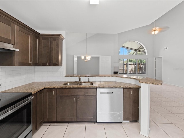 kitchen featuring appliances with stainless steel finishes, sink, light tile patterned floors, light stone counters, and dark brown cabinets