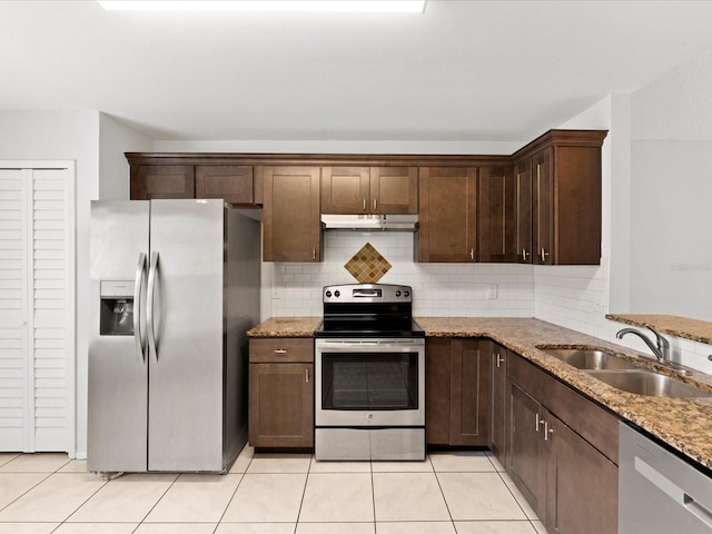 kitchen with light tile patterned flooring, sink, light stone counters, appliances with stainless steel finishes, and decorative backsplash