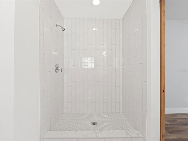 bathroom featuring hardwood / wood-style flooring and tiled shower