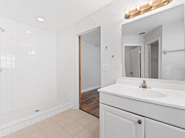 bathroom with a tile shower, vanity, and tile patterned flooring