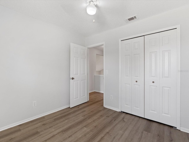 unfurnished bedroom featuring a textured ceiling, light wood-type flooring, and a closet