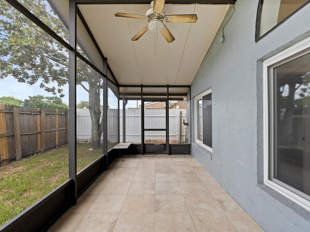 unfurnished sunroom with ceiling fan, vaulted ceiling, and a healthy amount of sunlight