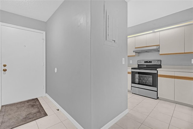 kitchen featuring white cabinetry, light tile patterned flooring, a textured ceiling, and electric stove