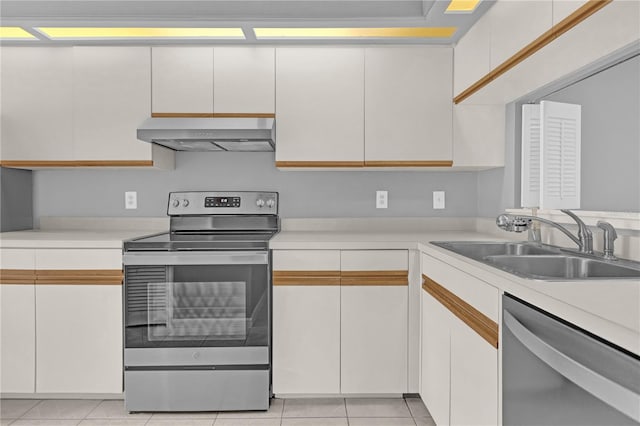 kitchen featuring sink, appliances with stainless steel finishes, white cabinetry, light tile patterned flooring, and wall chimney exhaust hood