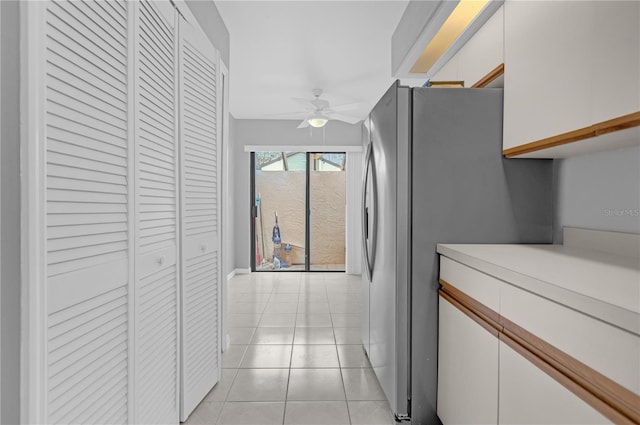 kitchen with white cabinetry, ceiling fan, stainless steel fridge, and light tile patterned floors