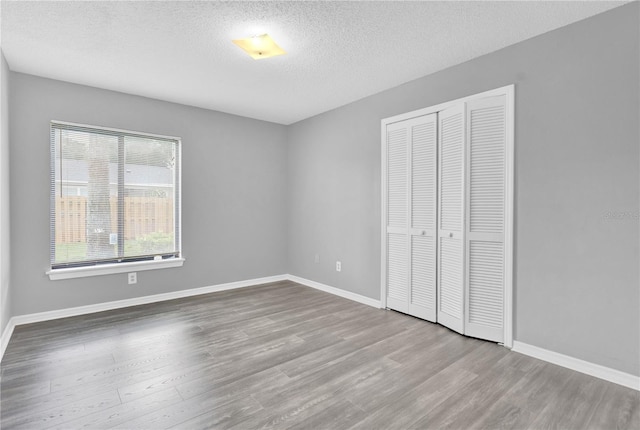 unfurnished bedroom featuring a closet, a textured ceiling, and light hardwood / wood-style floors