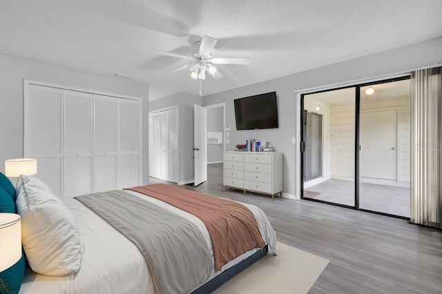 bedroom with hardwood / wood-style flooring, ceiling fan, access to exterior, a textured ceiling, and multiple closets