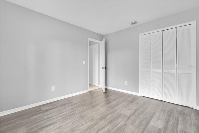 unfurnished bedroom with light wood-type flooring and a closet