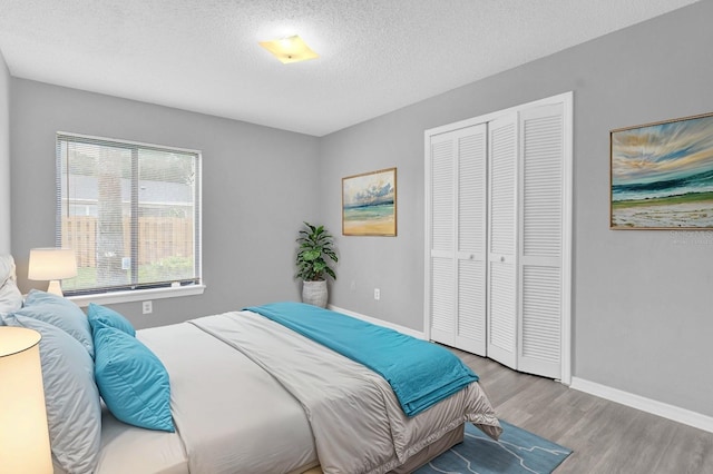 bedroom with light hardwood / wood-style floors, a closet, and a textured ceiling