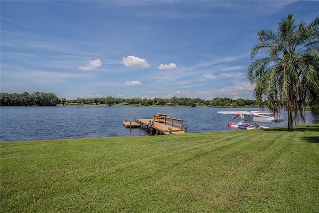 view of dock with a water view and a lawn