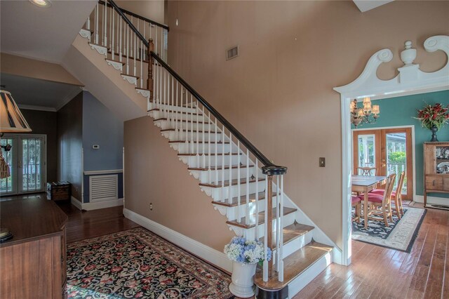 stairs featuring a towering ceiling, french doors, hardwood / wood-style floors, and crown molding