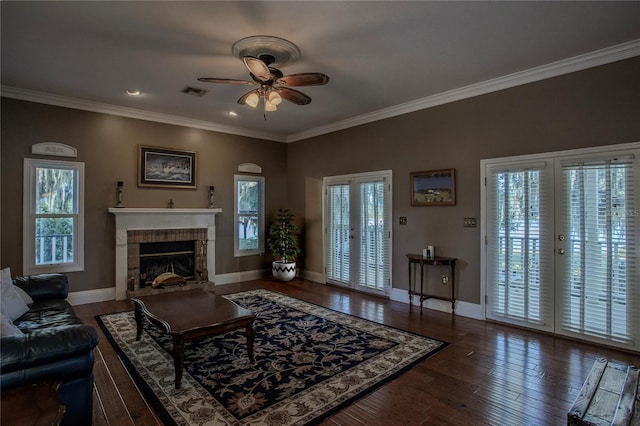 living room featuring ornamental molding, a fireplace, ceiling fan, and dark wood-type flooring