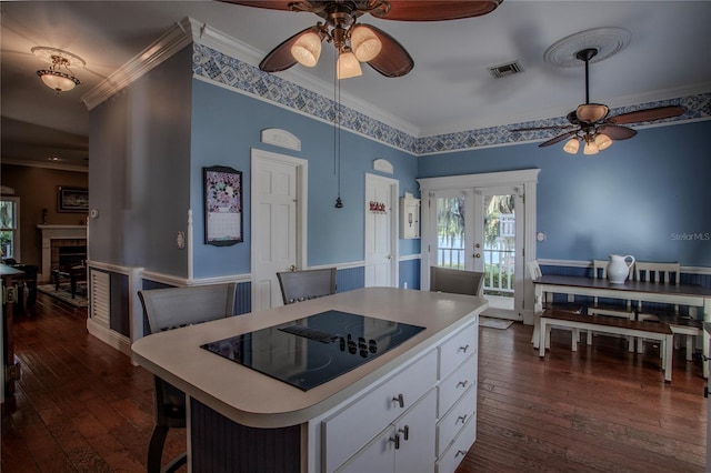 kitchen with black electric cooktop, ornamental molding, dark hardwood / wood-style floors, a kitchen island, and white cabinets