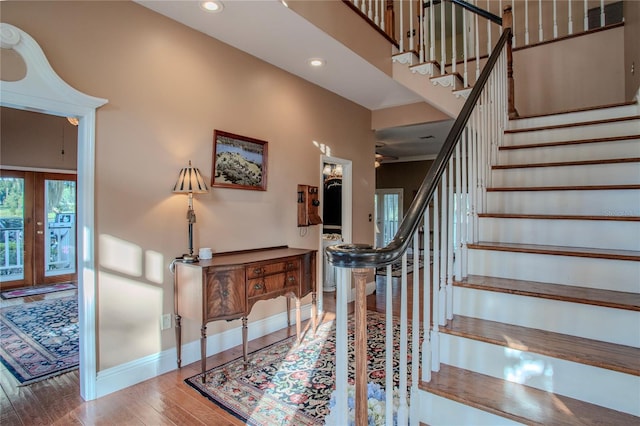 stairway with a towering ceiling, wood-type flooring, and french doors