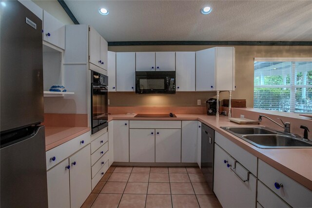 kitchen with white cabinetry, light tile patterned floors, a textured ceiling, black appliances, and sink