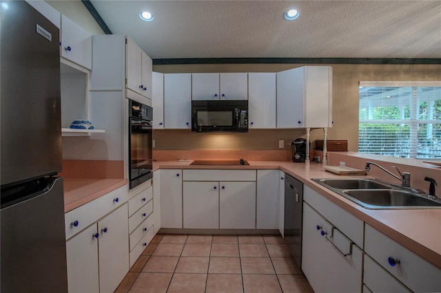 kitchen with sink, light tile patterned floors, white cabinetry, black appliances, and a textured ceiling