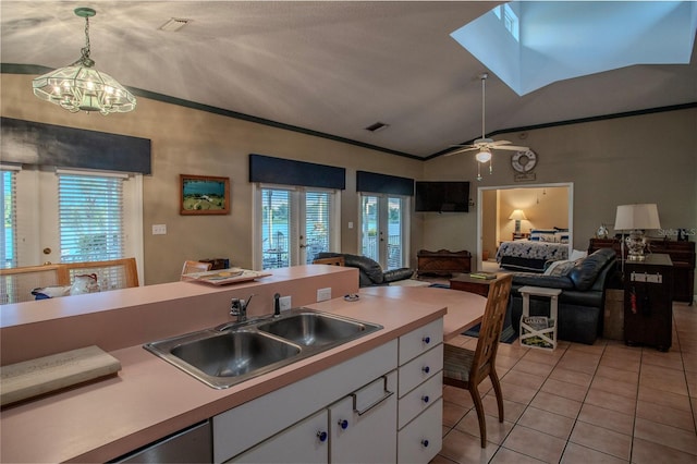 kitchen featuring sink, white cabinetry, vaulted ceiling, hanging light fixtures, and light tile patterned floors