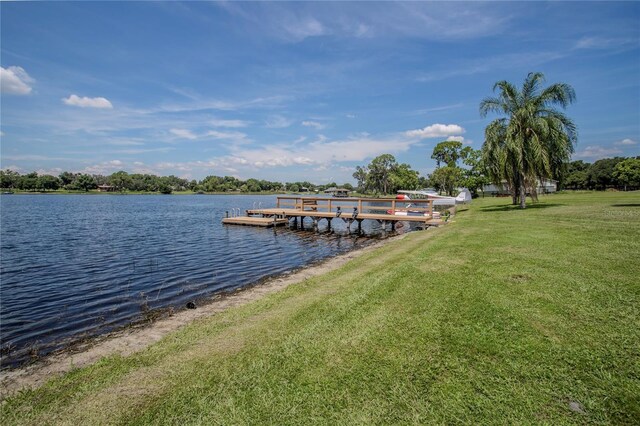 view of dock with a water view and a yard