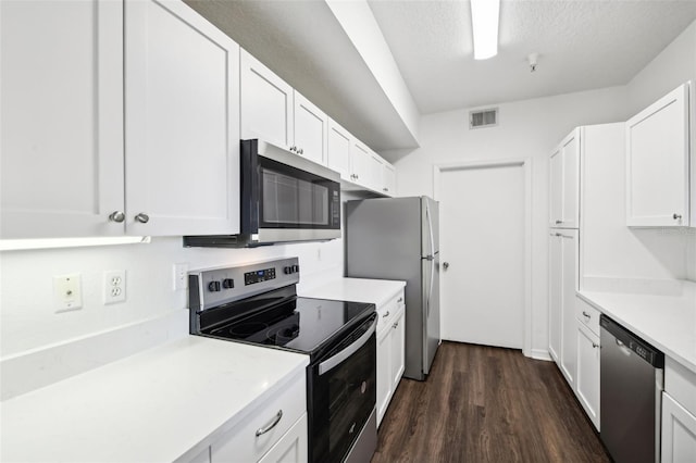 kitchen featuring dark wood-type flooring, a textured ceiling, stainless steel appliances, and white cabinetry