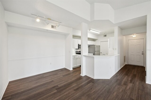 kitchen with stainless steel refrigerator, dark hardwood / wood-style flooring, white cabinetry, and track lighting