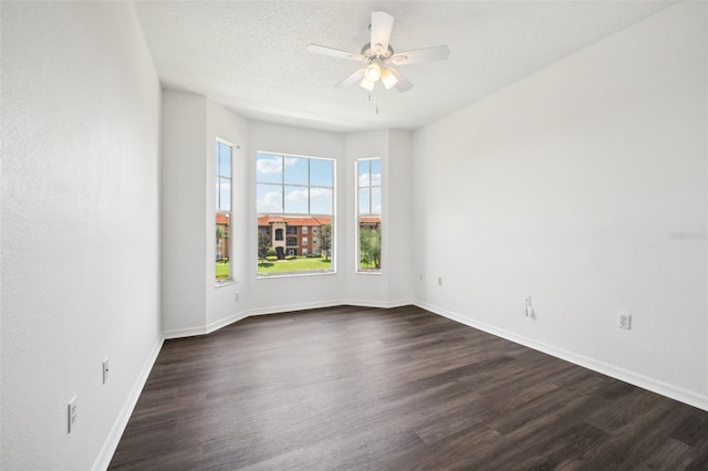 spare room with dark wood-style floors, ceiling fan, a textured ceiling, and baseboards