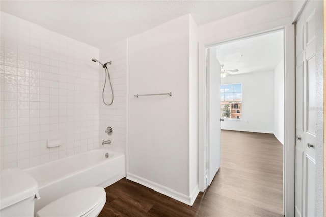 bathroom featuring baseboards, toilet, shower / washtub combination, and wood finished floors