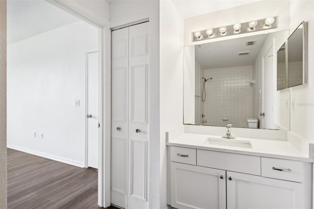 full bathroom with a closet, walk in shower, wood finished floors, and vanity