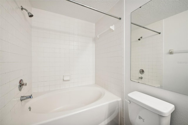 bathroom featuring toilet, tiled shower / bath combo, and a textured ceiling