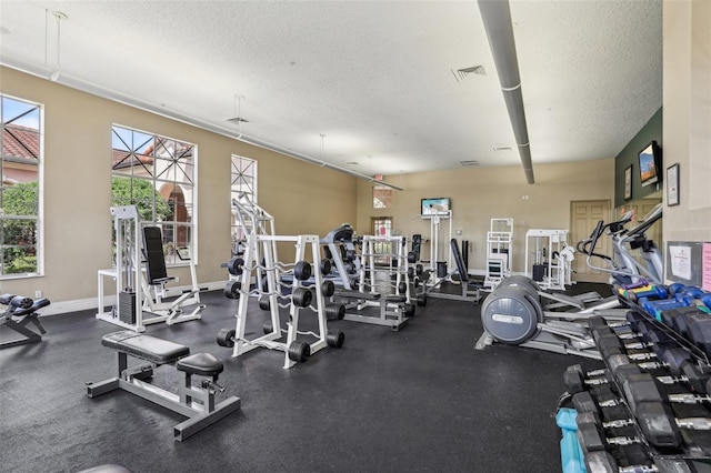 workout area featuring visible vents, a textured ceiling, and baseboards