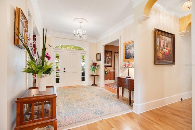 foyer featuring decorative columns, a chandelier, wood-type flooring, and ornamental molding