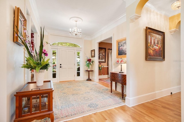 foyer entrance featuring ornamental molding, hardwood / wood-style floors, and a notable chandelier