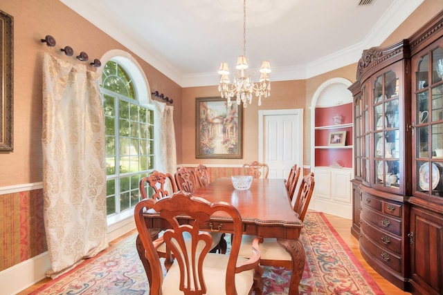 dining area featuring ornamental molding, a chandelier, light hardwood / wood-style floors, and built in shelves