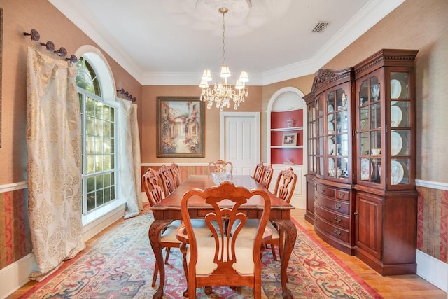 dining area with ornamental molding, a notable chandelier, and light hardwood / wood-style floors