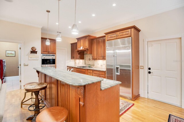 kitchen featuring appliances with stainless steel finishes, decorative light fixtures, a breakfast bar area, decorative backsplash, and a center island