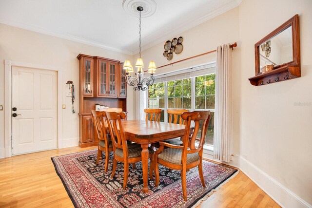 dining room with ornamental molding, an inviting chandelier, and light hardwood / wood-style flooring