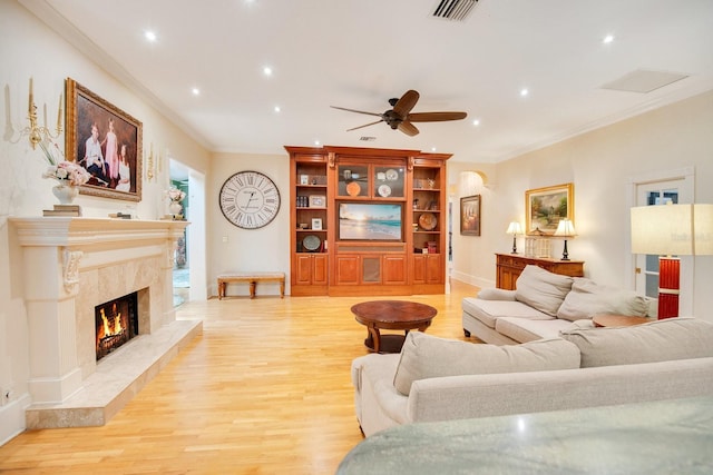 living room with crown molding, a fireplace, and light hardwood / wood-style floors