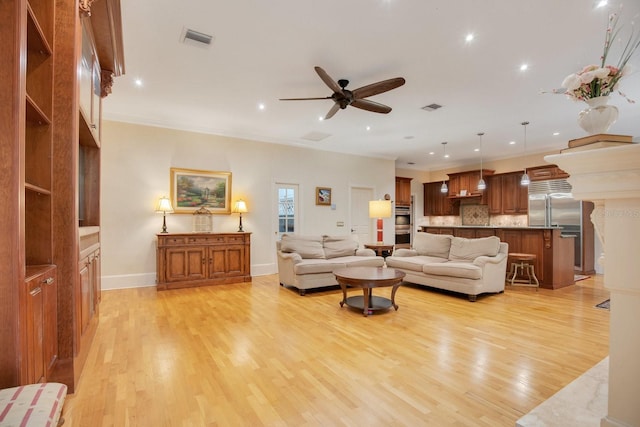 living room featuring crown molding, ceiling fan, and light wood-type flooring