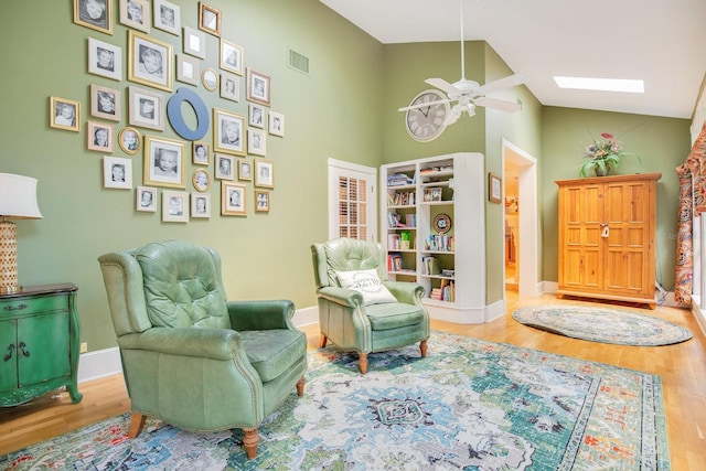 living area featuring wood-type flooring, ceiling fan, and a skylight