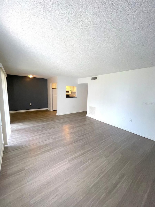 unfurnished living room featuring hardwood / wood-style flooring and a textured ceiling