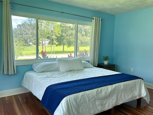 bedroom with multiple windows and dark hardwood / wood-style flooring