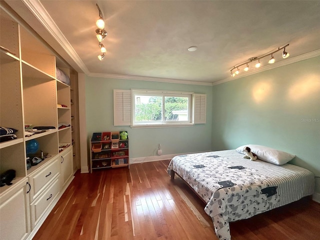 bedroom featuring crown molding, dark wood-type flooring, and rail lighting