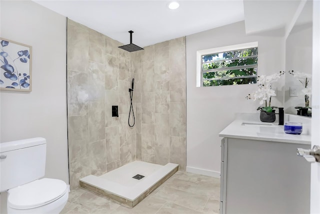 bathroom with tiled shower, vanity, tile patterned floors, and toilet