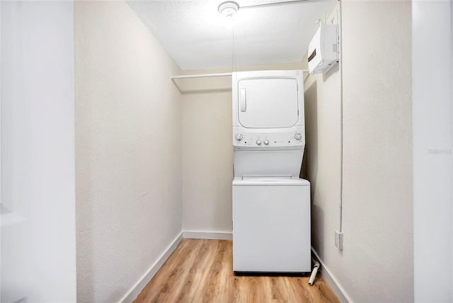 clothes washing area featuring light hardwood / wood-style flooring and stacked washer / drying machine