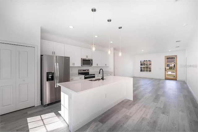 kitchen featuring pendant lighting, sink, white cabinets, a kitchen island with sink, and stainless steel appliances