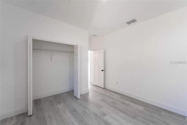 unfurnished bedroom featuring light hardwood / wood-style flooring and a closet