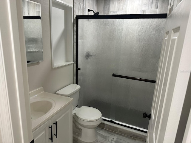 bathroom with toilet, an enclosed shower, and vanity