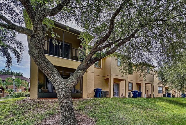 rear view of property with a balcony, central AC, and a lawn