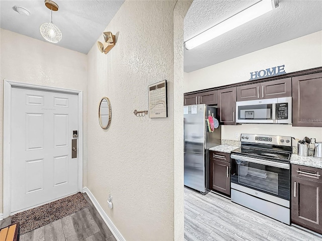 kitchen with stainless steel appliances, light hardwood / wood-style floors, light stone countertops, decorative light fixtures, and dark brown cabinetry