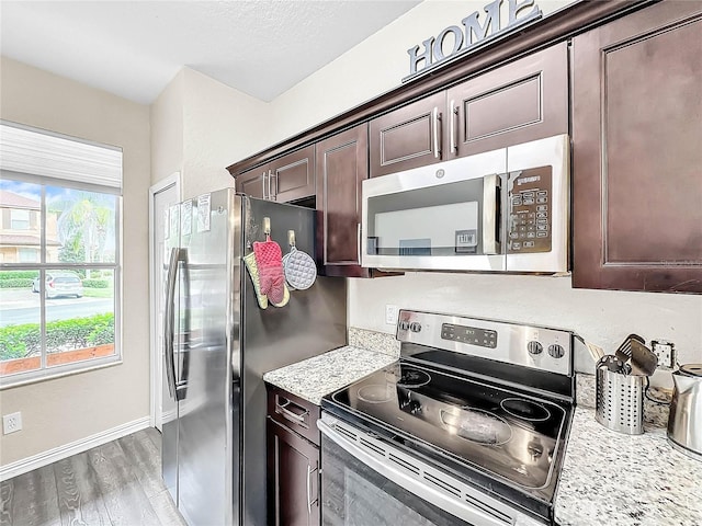 kitchen with light stone counters, hardwood / wood-style flooring, dark brown cabinets, and appliances with stainless steel finishes